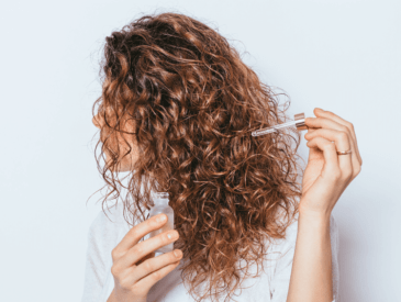 woman applying oil to natural curly hair