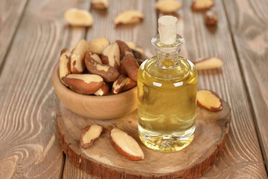 wooden bowl of brazil nuts and glass bottle of brazil nut oil
