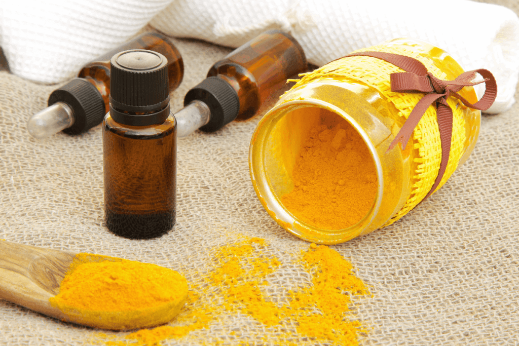 jar of spilled turmeric powder and 3 essential oil bottles