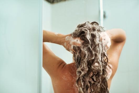 woman shampooing hair and massaging the scalp for hair growth