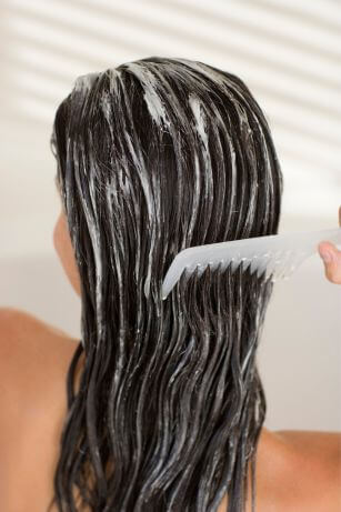 woman with hair mask, detangling hair with wide tooth comb