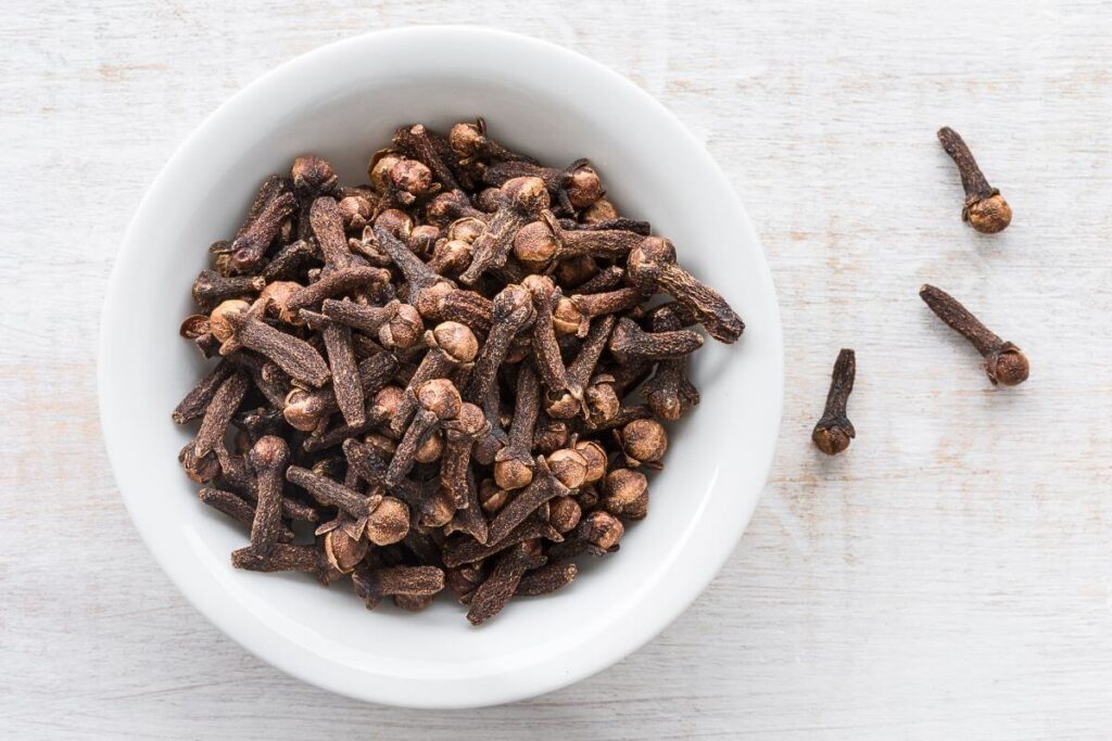 white bowl of whole cloves for hair rinse recipe