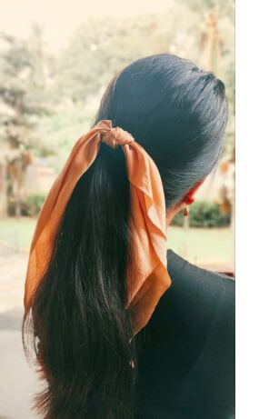 woman with dark hair wearing scarf around ponytail
