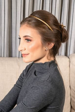 woman with brown hair wearing headband and low bun hairstyle