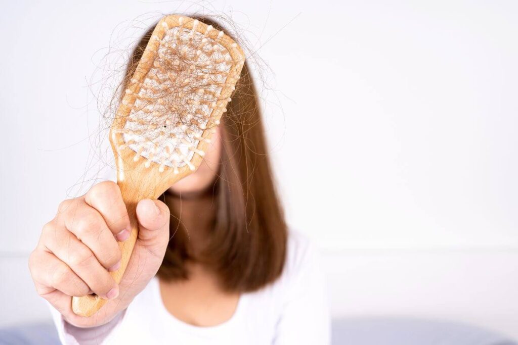 woman holding wooden hair brush full of shed hair