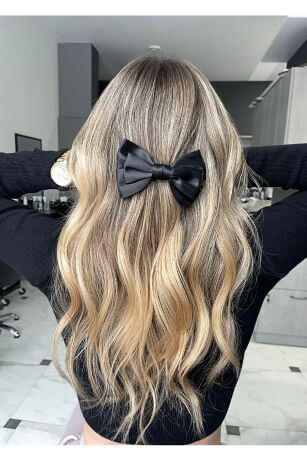 blonde hair in half up hairstyle with black bow