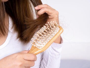 woman brushing shed hair with wooden hair brush
